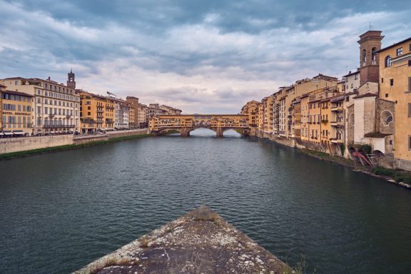 Die Ponte Vecchio über den Arno mit historischen Gebäuden im Hintergrund.